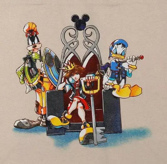A beige canvas tote bag featuring a colorful graphic print of Disney Kingdom characters including Goofy, Donald Duck, and Pluto standing in front of a silver throne.