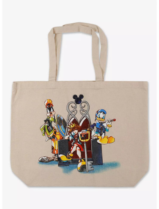 A beige canvas tote bag featuring a colorful graphic print of Disney Kingdom characters including Goofy, Donald Duck, and Pluto standing in front of a silver throne.