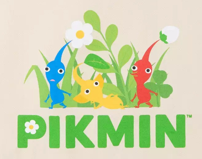 A beige canvas tote bag featuring a colorful graphic of Pikmin characters in green grass with the word 'PIKMIN' printed below in green, on a clean white background.