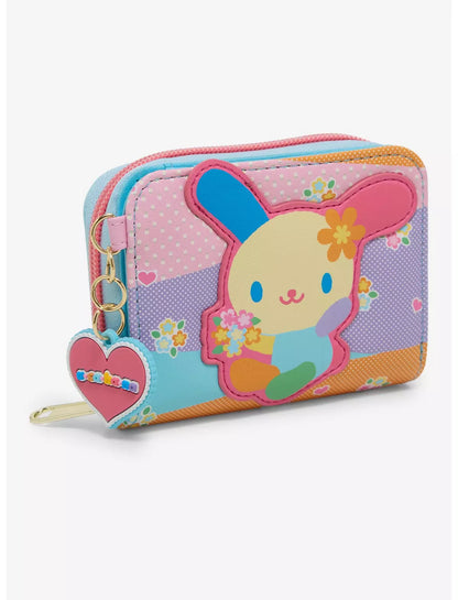A pastel-colored zip-around coin purse featuring a cute bunny character patch on the front, floral details, and a dangling heart-shaped charm with colorful lettering, shown on a clean white background.