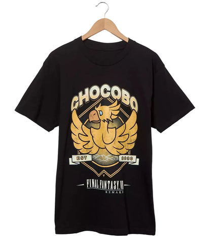 A black short-sleeve graphic T-shirt hanging on a wooden hanger against a light gray background. The shirt features a large gold and beige chakra-style bird graphic with the text 'CHOCOBO' and 'Final fantasy' on the front.