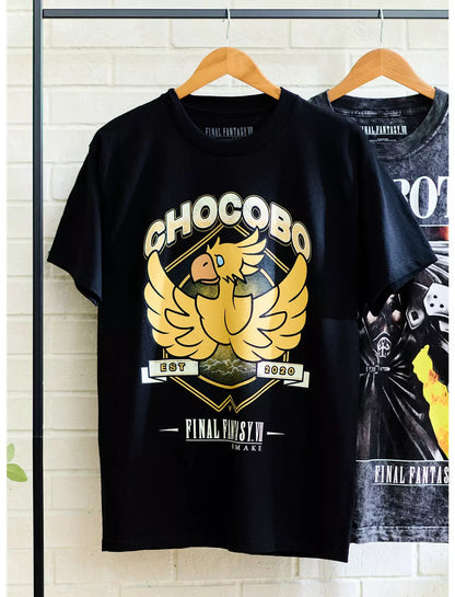 A black short-sleeve graphic T-shirt hanging on a wooden hanger against a light gray background. The shirt features a large gold and beige chakra-style bird graphic with the text 'CHOCOBO' and 'Final fantasy' on the front.