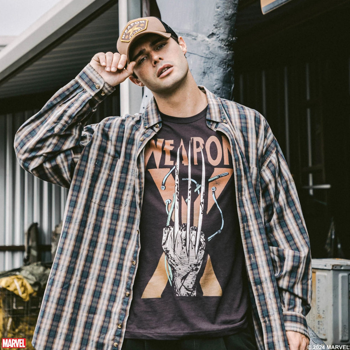 Man wearing a plaid shirt over a graphic t-shirt with a Marvel logo.