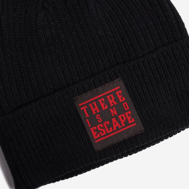 A black Star wars ribbed knit beanie hat featuring a red and black circular Star Wars Galactic Empire crest patch on the front cuff, with a small white embroidered logo on the side, shown against a light gray background.