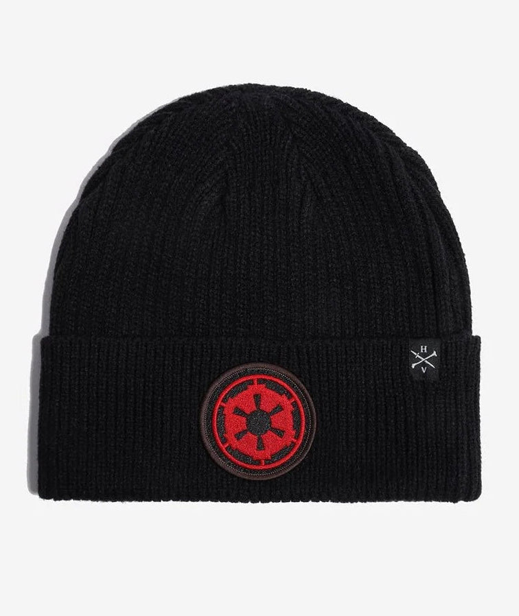 A black Star wars ribbed knit beanie hat featuring a red and black circular Star Wars Galactic Empire crest patch on the front cuff, with a small white embroidered logo on the side, shown against a light gray background.