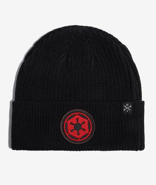 A black Star wars ribbed knit beanie hat featuring a red and black circular Star Wars Galactic Empire crest patch on the front cuff, with a small white embroidered logo on the side, shown against a light gray background.