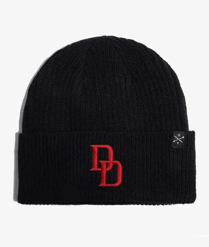 A black ribbed knit Marvel Daredevil beanie hat featuring a red embroidered 'DD' logo on the front cuff and a small black square brand tag on the right side, set against a plain white background.