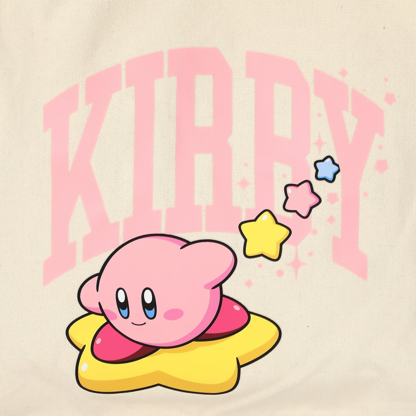 A close-up of a light beige fabric featuring a printed graphic of Kirby sitting on a yellow star, with large pink text reading 'KIRBY' behind him and small colorful stars.
