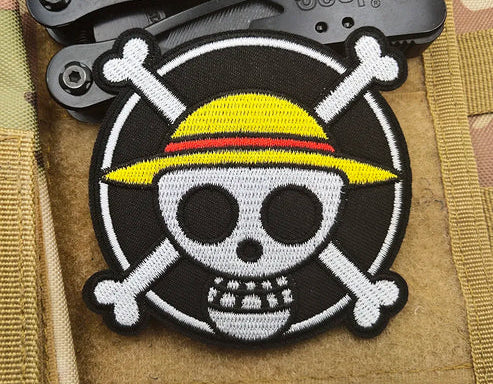 One Piece Starw hat crew Skull and crossbones patch with yellow hat on a Jeep branded knife, on a camouflage background