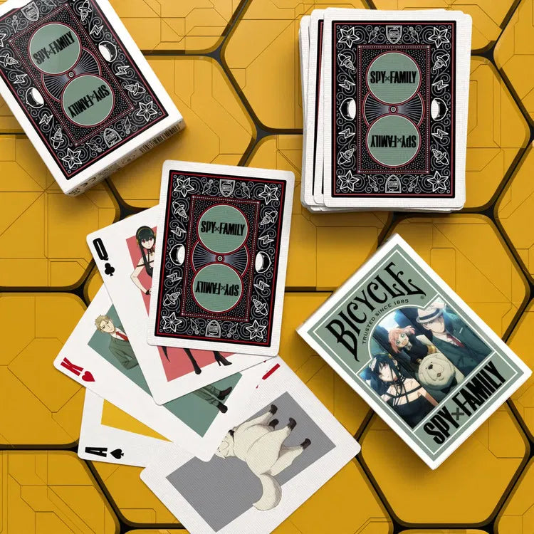 Playing cards with 'Spy Family' and 'Bicycle' branding on a yellow geometric patterned surface.