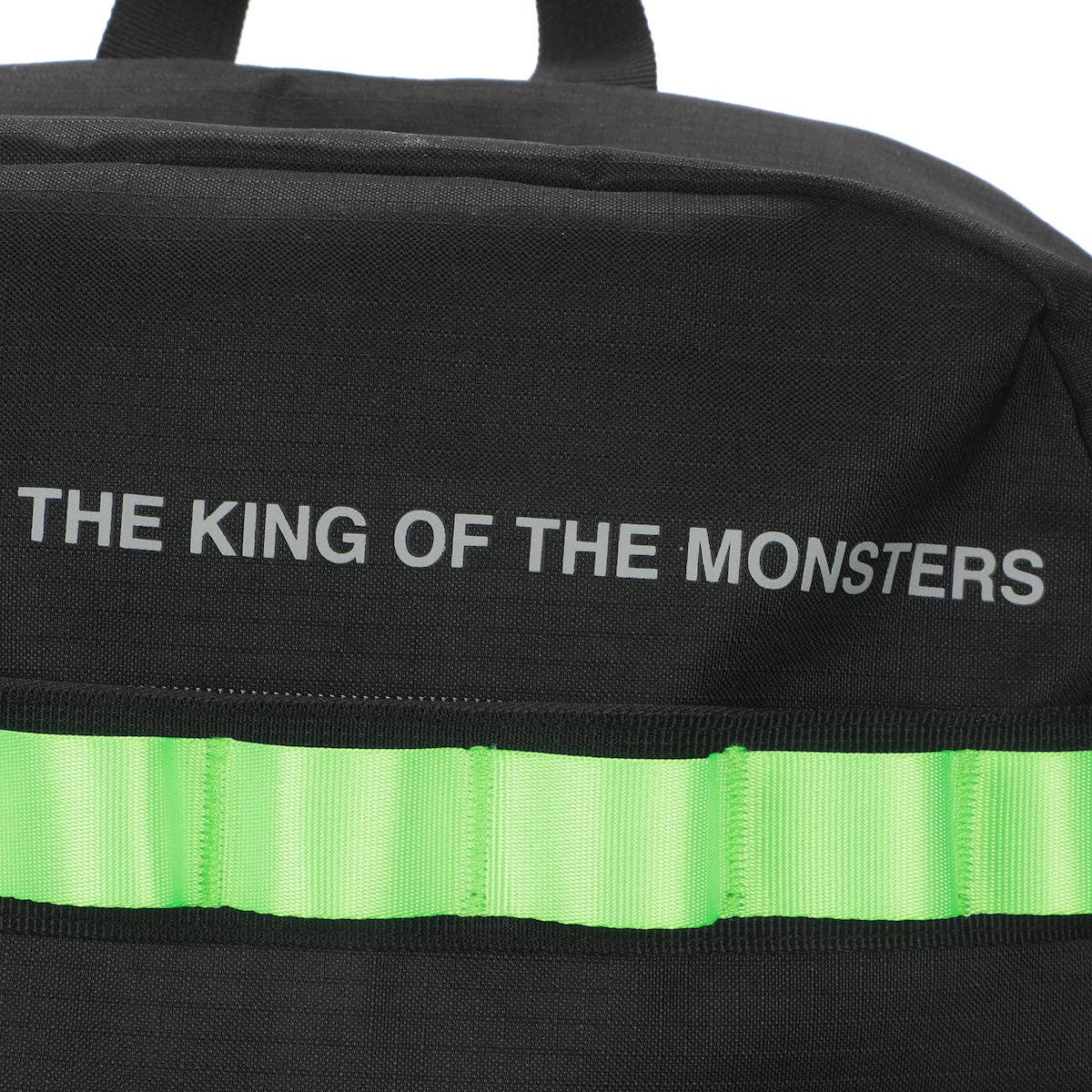 Black bag with 'The King of the Monsters' text and green stripe on a white background