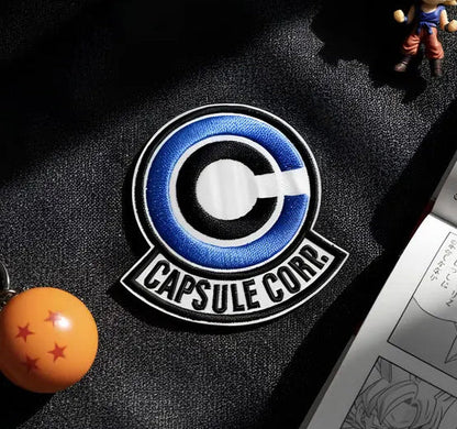 Keychain with a 'Capsule Corp' logo and a small figurine on a dark surface.