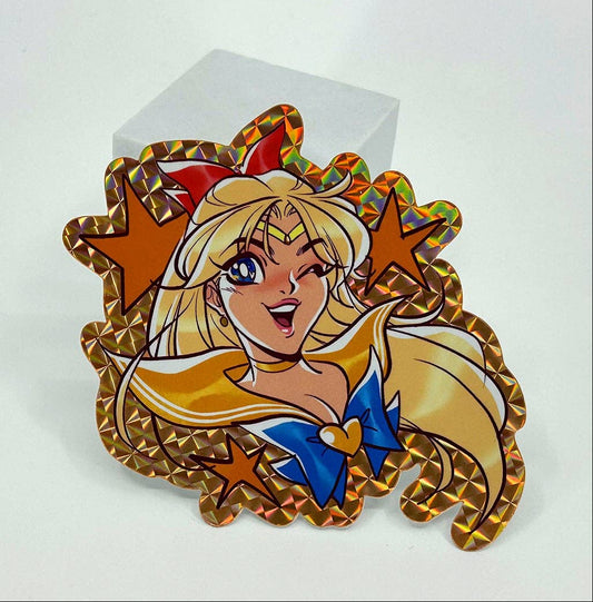 An anime Sailor Moon Sailor Scout Venus holographic sticker displayed on a small white block against a clean white background.