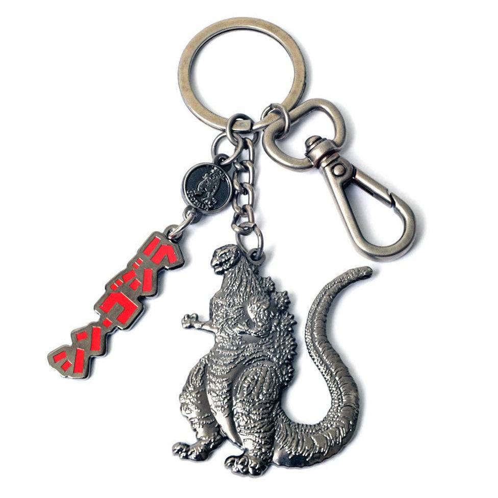 A metal keychain featuring a detailed silver Godzilla figure, a red and black Japanese katakana 'Godzilla' charm, and a silver clasp on a white background.